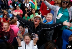 Inocencia Polanco, of Philadelphia and originally form the Dominican Republic, center in hat, joined by Freddy Espana of Honduras, left in striped shirt, and Maria Zuleta of Columbia, low center in white, pray a novena together as they wait for Pope Fran