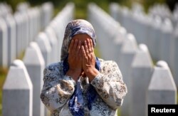 A woman prays at a graveyard, ahead of a mass funeral in Potocari near Srebrenica, Bosnia and Herzegovina July 11, 2020. Bosnia marks the 25th anniversary of the massacre of more than 8,000 Bosnian Muslim men and boys, with many relatives unable to attend