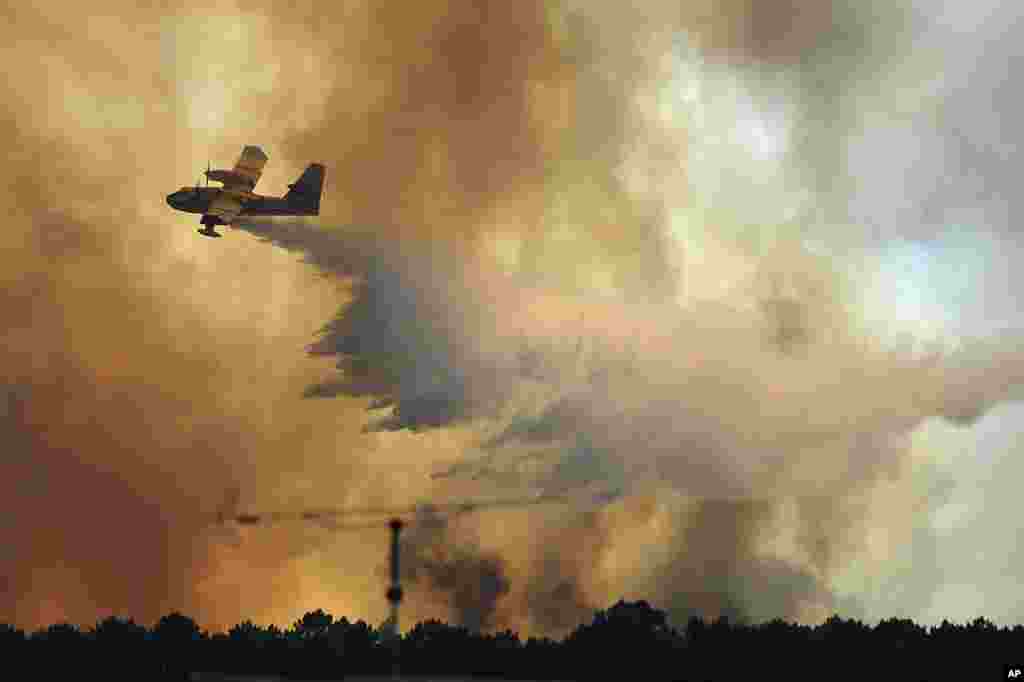 A fire fighting aircraft drops water over a fire outside the village of Pedrogao Grande central Portugal. . More than 2,000 firefighters battled to contain major wildfires in the central region of the country, where one blaze killed dozens of people.