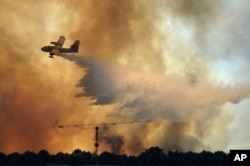 A fire fighting aircraft drops water over a fire outside the village of Pedrogao Grande central Portugal, June 19, 2017.