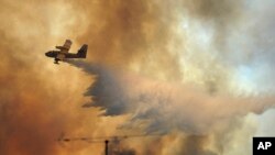 Sebuah pesawat pemadam kebakaran menyiramkan air di atas kobaran api kebakaran hutan di luar desa Pedrogao Grande, Portugis tengah (19/6).