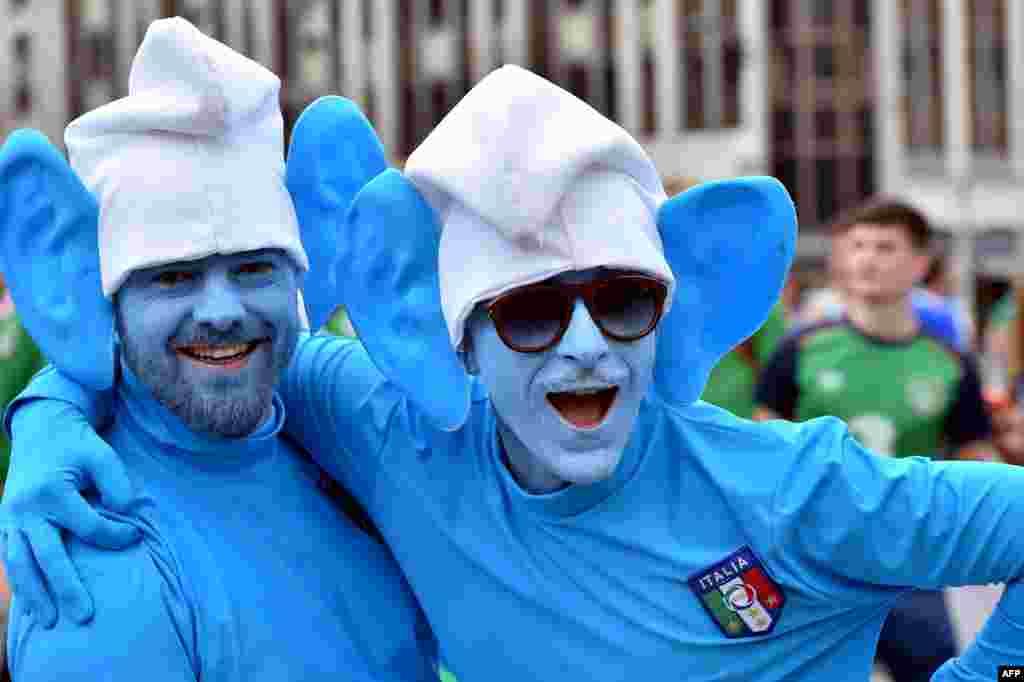Dua dari pendukung tim sepakbola Italia, berdandan a la tokoh kartun Smurf, berkumpul bersama pendukung sepakbola lainnya di jalan-jalan Lille, Perancis menjelang pertandingan sepakbola Grup E Piala Eropa 2016 antara Italia dan Irlandia.
