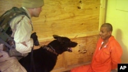 This image obtained by The Associated Press shows Sgt. Michael Smith, left, with his dog, watching a detainee at an unspecified date in 2003 at the Abu Ghraib prison in Baghdad, Iraq.