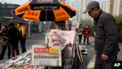 A man looks at a newsstand with a copy of the day's Global Times displayed on a basket in Beijing, China, Tuesday, April 5, 2016.