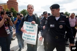 Russian police detane gay rights activist Peter Tatchell, center, as he holds a banner that reads "Putin fails to act against Chechnya torture of gay people" near Red Square in Moscow, Russia, June 14, 2018.