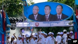 FILE PHOTO- Supporters of Prime Minister Hun Sen's Cambodian People's Party dance under portraits of the party leaders, from left, Chea Sim, Hun Sen and Heng Samrin, during an election campaign in Phnom Penh, Cambodia, Thursday, June 27, 2013. 