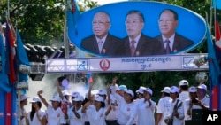 Người ủng hộ Thủ tướng Hun Sen và đảng Nhân dân đứng dưới chân dung các lãnh đạo đảng. Từ trái: Chea Sim, Thủ tướng Hun Sen và ông Heng Samrin trong một chiến dịch tranh cử tại Phnom Penh.
