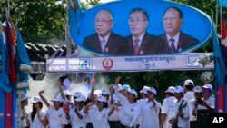 Supporters of Prime Minister Hun Sen's Cambodian People's Party dance under portraits of the party leaders, from left, Chea Sim, Hun Sen and Heng Samrin, during an election campaign in Phnom Penh, file photo. 