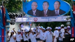 Supporters of Prime Minister Hun Sen's Cambodian People's Party dance under portraits of the party leaders, from left, Chea Sim, Hun Sen and Heng Samrin, during an election campaign in Phnom Penh, file photo. 