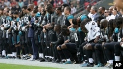 Jacksonville Jaguars players lock arms and kneel down during the playing of the U.S. national anthem before an NFL football game against the Baltimore Ravens at Wembley Stadium in London, Britain, Sept. 24, 2017. 