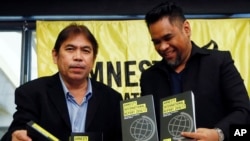 Amnesty International, Philippines' Jose Noel Olano, left, and Wilnor Papa, hold copies of the 2016/17 Amnesty International report which they released at a news conference, Feb. 22, 2017, in suburban Quezon city northeast of Manila, Philippines. 