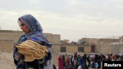 A woman holds bread in Minbij city in the east countryside of Aleppo, Syria, Oct. 18, 2013.