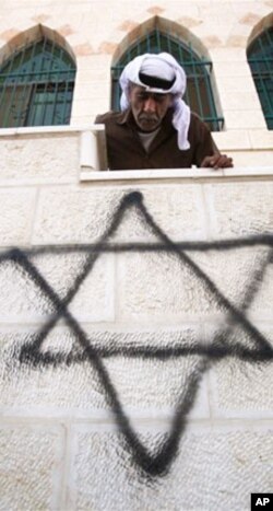 A Palestinian man looks down on graffiti of the Star of David spray-painted on a wall of a West Bank mosque, September 5, 2011.