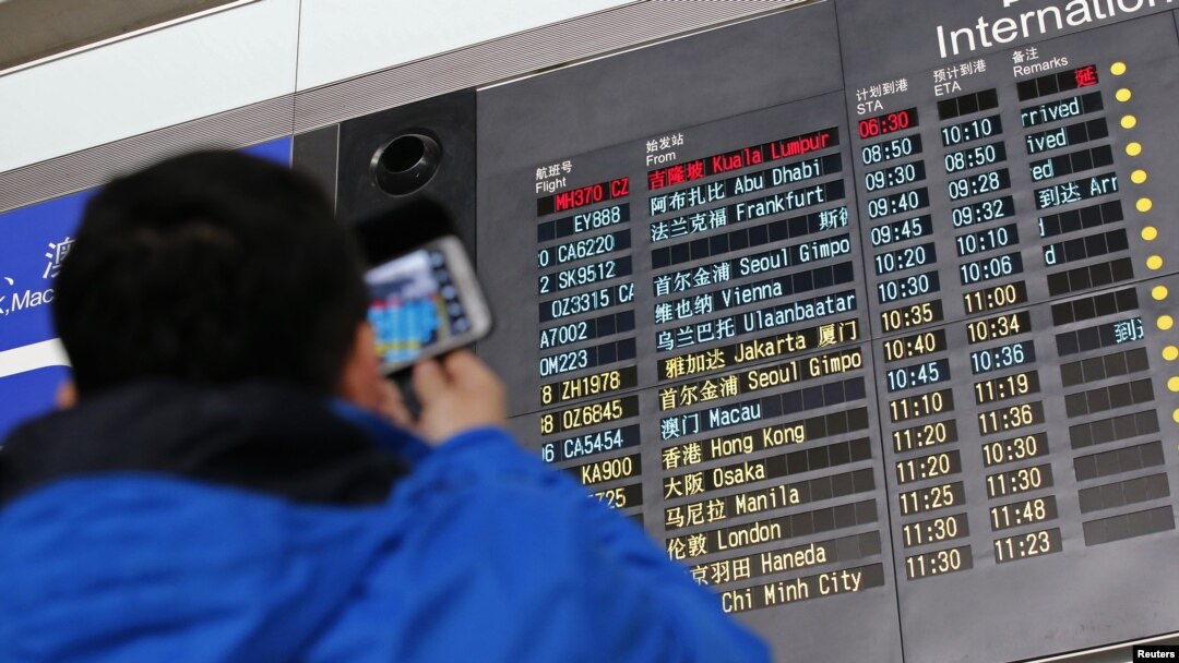 Seorang pengunjung memotret papan informasi jadwal kedatangan pesawat Malaysia Airlines dengan nomor penerbangan MH370 (atas, berwarna merah) di Bandara Internasional Beijing, 8 Maret 2014.