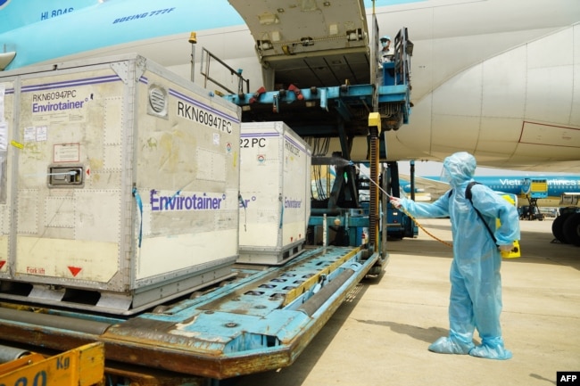 A health official sprays disinfectant on the first batch of AstraZeneca/Oxford Covid-19 coronavirus vaccine shipment after its arrival at the Tan Son Nhat airport in Ho Chi Minh city on February 24, 2021. (Photo by Phu Nguyen / AFP)