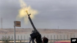 An anti-Gadhafi rebel fires on a government warplane flying overhead in Ras Lanuf, eastern Libya, March 9, 2011