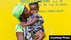 Mamie Harris, a caregiver at Liberia’s Hawa Massaquoi transit center in Unification Town, Margibi County, holds 18-month-old Agnes. The center, run by the government with UNICEF support, aids children affected by Ebola. (© UNICEF /Jallanzo)