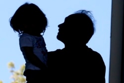 In this April 22, 2020, photo, Afghan refugee Mahmood Amiri carries his daughter, Safa, in West Valley City, Utah.