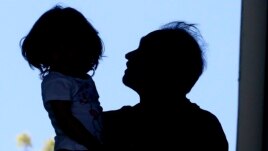In this April 22, 2020, photo, Afghan refugee Mahmood Amiri carries his daughter, Safa, in West Valley City, Utah.