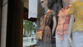 A passer-by walks past garments displayed on mannequins in a storefront window, Thursday, June 11, 2020, in Boston, Massachusetts. (AP Photo/Steven Senne)