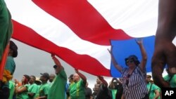 Puertorriqueños levantan una bandera de su isla durante una protesta el Primero de Mayo contra inminentes medidas de austeridad en medio de una agobiante crisis económica.