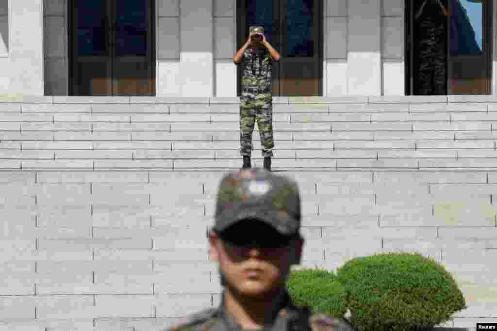 A North Korean soldier looks toward the south as a South Korean soldier stands guard in the truce village of Panmunjom inside the Demilitarized Zone separating the two Koreas, South Korea.