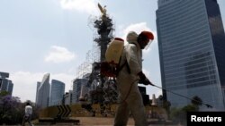 Un empleado de Ciudad de México desinfecta una zona colindante al Ángel de lndependencia en medio de la crisis de la COVID-19.
