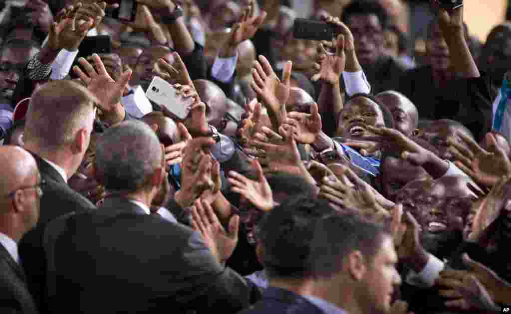 A Kenyan woman reaches out across a sea of hands as she tries to shake the hand of President Barack Obama, as he walks past the crowd after delivering a speech at the Safaricom Indoor Arena in the Kasarani area of Nairobi, Kenya.