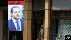 FILE - A poster of resigned Lebanese Prime Minister Saad Hariri with Arabic that read, "We are all with you," hangs on a street in Beirut, Lebanon, Nov. 13, 2017. 