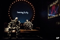 Mannequins in "a lightbulb suit" are photographed in front of a "Learning to Fly" display at the Pink Floyd exhibition 'Their Mortal Remains.'