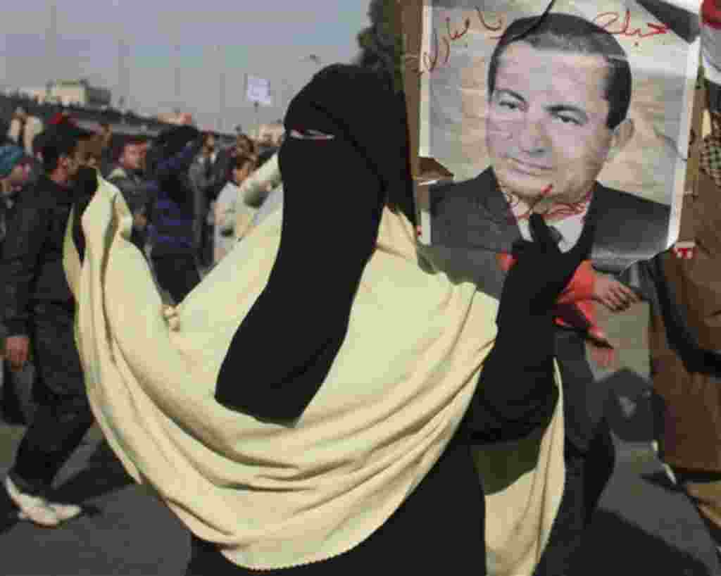 A pro-government supporter holds a portrait of Egyptian President Hosni Mubarak in Cairo, Egypt, Wednesday, Feb.2, 2011. Several thousand supporters of President Hosni Mubarak, including some riding horses and camels and wielding whips, clashed with anti