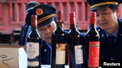 Police officers check bottles of confiscated fake wines before destroying them in Xi'an, Shaanxi province Jan. 4, 2012.