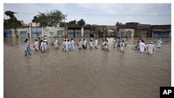 This photograph shows (top) residents returning to the town of Nowshera, northwest Pakistan, as flood waters started to recede on Aug. 1, 2010; and (bottom) a man and boy as they ride past the same exact location nearly a year after the floods ravaged one