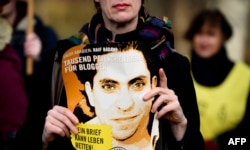 FILE - An Amnesty International activist holds a picture of Saudi blogger Raif Badawi during a protest against his flogging punishment, in front of Saudi Arabia's embassy in Berlin, Germany, Jan. 29, 2015.