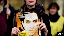 FILE - An Amnesty International activist holds a picture of Saudi blogger Raif Badawi during a protest against his flogging punishment, in front of Saudi Arabia's embassy in Berlin, Germany, January 29, 2015.