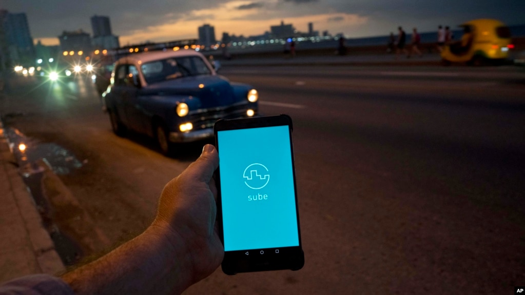 A man holds his phone showing the app "Sube," a ride-hailing app for the aging American sedans on the streets of Havana, in Havana, Cuba, Feb. 21, 2019.