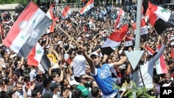 Supporters of Syrian President Bashar al-Assad wave national flags after his speech in Damascus June 20, 2011, in this handout photograph released by Syria's national news agency SANA