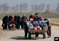 FILE - Iraqi civilians walk toward Iraqi security forces after fleeing their homes due to fighting between government forces and Islamic State militants, on the western side of Mosul, Iraq, March 9, 2017.