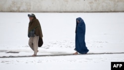 An Afghan couple walk through the snow in the courtyard of the the famous Blue Mosque in Mazar-i-sharif, Nov 24, 2016.