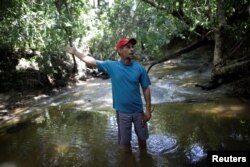 FILE - Subsistence farmer Ronivon Matias de Andrade walks in an area of a stream that supplies his community with drinking water at farm in Palmeirante, Brazil, Feb. 16, 2018.