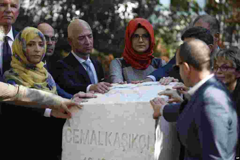 Hatice Cengiz, center, the fiancee of slain Saudi journalist Jamal Kashoggi, accompanied by his colleagues and friends including The Washington Post owner Jeff Bezos, unveil a plaque, near the Saudi Arabia consulate in Istanbul, Turkey, marking the one-year anniversary of his death.