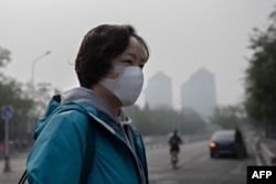 A woman wears a protective mask to fight bad air pollution in Beijing on October 22, 2018. (Photo by Nicolas ASFOURI / AFP)