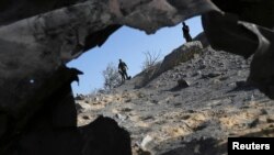 Militan Palestina memeriksa apa yang dikatakan polisi sebagai serangan udara balasan Israel di Khan Younis, selatan Gaza, 29 Juni 2014.
