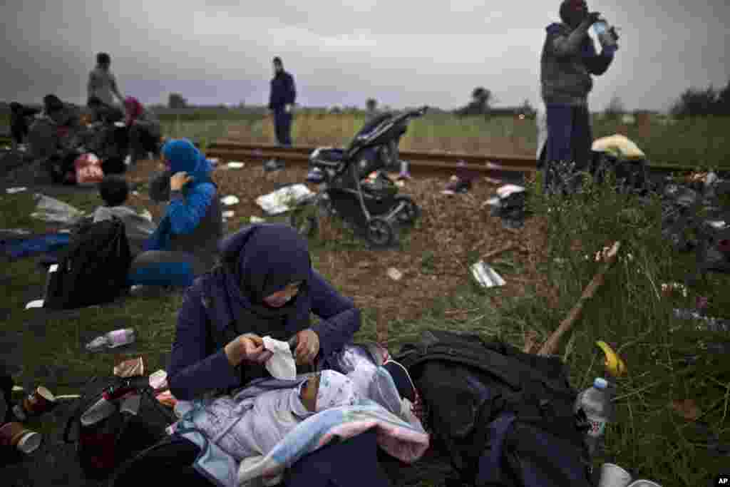 Iraqi refugee Umm Fadil, tends to her crying son, while resting by a railway track after they crossed the Serbian-Hungarian border near Roszke, southern Hungary. EU officials and human rights groups say they&#39;ve been disappointed by the animosity toward asylum-seekers in countries from which hundreds of thousands of people fled communist dictatorships just decades ago.