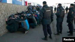 Russian police detain migrant workers during a raid at a vegetable warehouse complex in the Biryulyovo district of Moscow, Oct. 14, 2013.