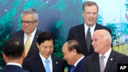 Vietnamese Prime Minister Nguyen Xuan Phuc (center right) shakes hands with Chinese Minister of Commerce Zhong Shan (center left) as Philippine Trade Secretary Ramon Lopez (top left) U.S Trade Representative Robert Lighthizer (top right) and Peruvian Trade Minister Eduardo Ferreyros (bottom right) gather for a group photo at the Asia-Pacific Economic Cooperation (APEC) Trade ministerial meeting in Hanoi, Vietnam, May 20, 2017.