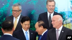 Vietnamese Prime Minister Nguyen Xuan Phuc, center right, shakes hands with Chinese Minister of Commerce Zhong Shan, center left, as Philippine Trade Secretary Ramon Lopez, top left, U.S Trade Representative Robert Lighthizer, top right, and Peruvian Trade Minister Eduardo Ferreyros, bottom right, look on after a group photo at the Asia-Pacific Economic Cooperation (APEC) Trade ministerial meeting in Hanoi, Vietnam on Saturday, May 20, 2017.