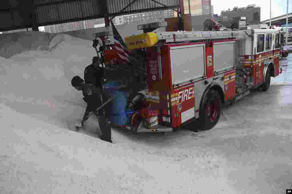 Firefighters load salt onto a container in the back of their truck at a Sanitation Department depot in New York, Feb. 8, 2013.