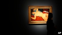FILE - A member of staff at Christie's auction house looks at a painting by Italian artist Amedeo Modigliani entitled 'Ne Couche' 1917-1918 as it goes on show in London. The painting sold for $170.4 million in New York.