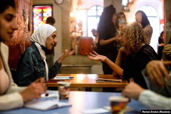 Seorang perempuan Palestina mengobrol dengan seorang perempuan Israel selama program pertukaran bahasa dengan model kencan kilat, di Yerusalem, 27 Oktober 2021. (Foto: REUTERS/Ronen Zvulun)